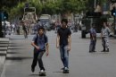 Two youths on skateboards pass by a police officer and a soldier securing a street they have closed off, where anti-Hezbollah activists had earlier held a protest, in Beirut