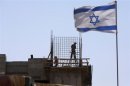 An Israeli flag is seen as labourers work on a construction site in a Jewish settlement near Jerusalem