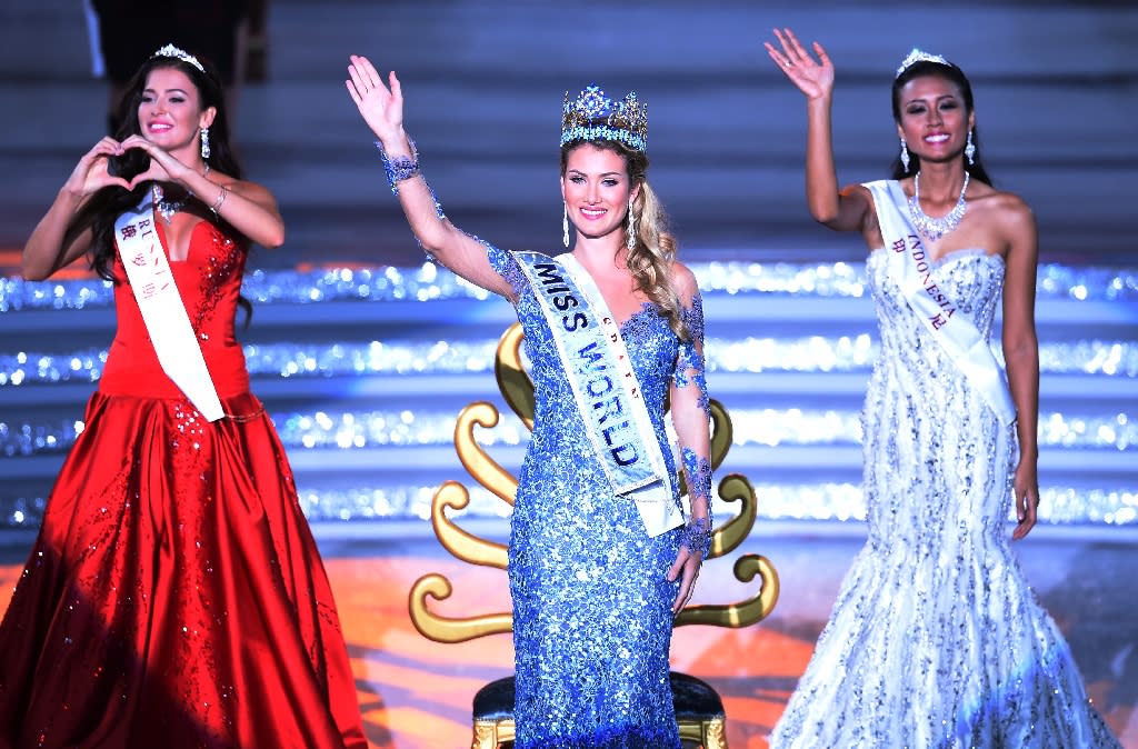 Mireia Lalaguna Rozo (C) of Spain waves after winning the new title at the Miss World Grand Final in Sanya, next to Miss Russia, Sofia Nikitchuk (L) and Miss World Indonesia, Maria Harfanti (R) in southern China&#39;s Hainan province on December 19, 2015