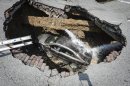 This photo provided by the Toledo, Ohio Fire and Rescue Department shows a car at the bottom of a sinkhole caused by a broken water line in Toledo, Ohio on Wednesday, July 3, 2013. Police say the driver, 60-year-old Pamela Knox of Toledo, was shaken up and didn't appear hurt but was taken to a hospital as a precaution. (AP Photo/Toledo, Ohio Fire and Rescue Department, Lt. Matthew Hertzfeld)
