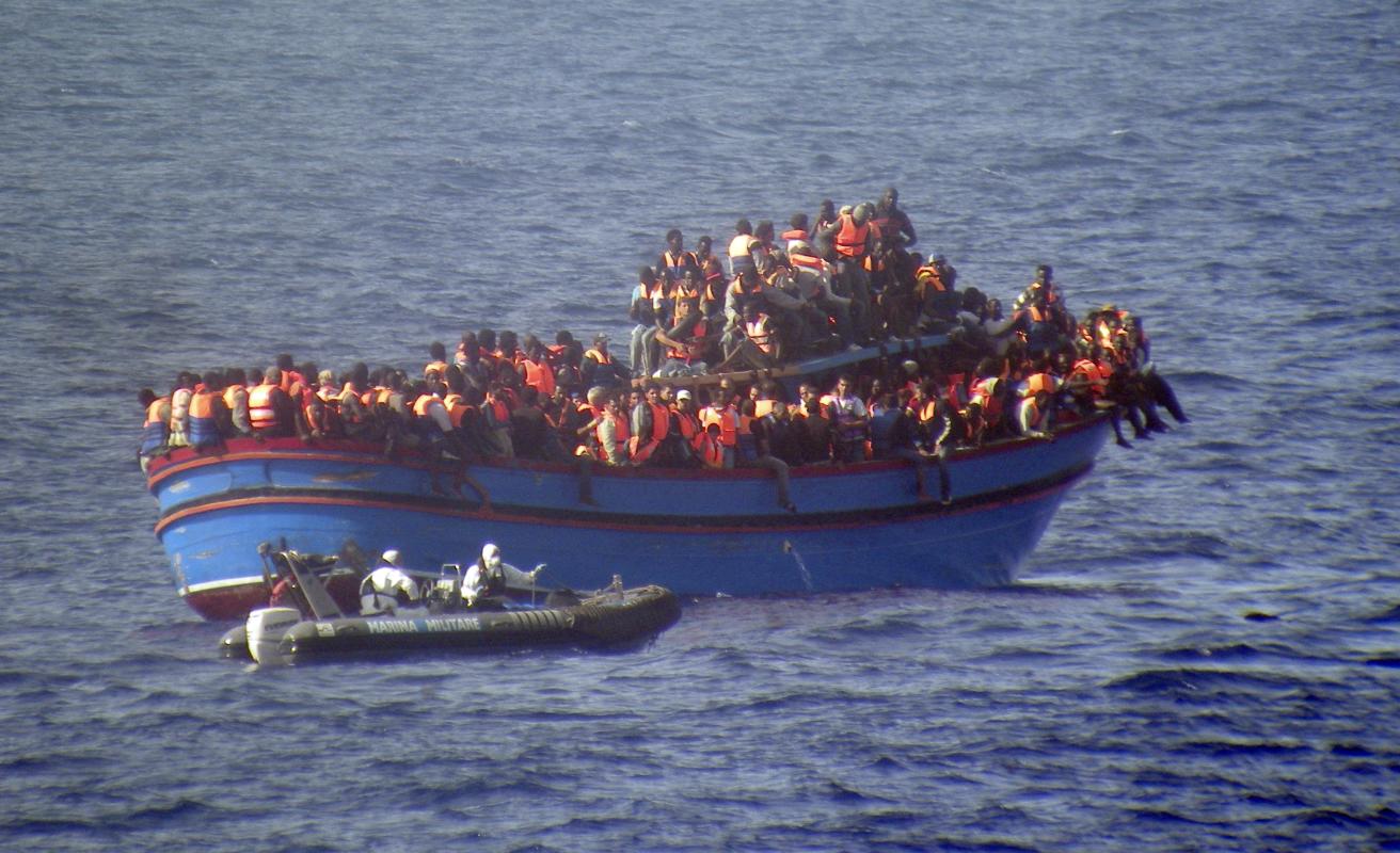 FILE - In this June 29, 2014 file photo released by the Italian Navy a motor boat from the Italian frigate Grecale approaches a boat overcrowded with migrants in the Mediterranean Sea. The bodies of some 30 would-be migrants were found in in the hold of a packed smugglers' boat that was carrying nearly 600 people making its way to Italy.  (AP Photo/Italian Navy, ho)