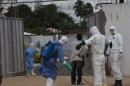 Health workers wearing protective equipment are disinfected outside the Island Clinic in Monrovia, where patients are treated for Ebola