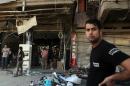 An Iraqi man stands in front of a damaged shop in Baghdad's Karrada district on May 3, 2015