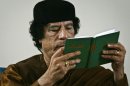 FILE - In this Friday, March 2, 2007 file photo, Libya's Moammar Gadhafi holds a copy of the Green Book during a debate on the sidelines of celebrations marking the 30-year anniversary of the declaration of the "jamahiriya," or "rule of the masses", in Sabha, Libya. A new law that excludes former officials of the Moammar Gadhafi era from public office is dividing Libya and deepening the turmoil that has plagued the country since the civil war that ousted the erratic leader. Passed by lawmakers essentially at gunpoint, it bans not just those who held office but even clerics who glorified the dictator and researchers who worked on his notorious political tract, the Green Book. (AP Photo/Nasser Nasser, File)