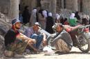 Syrian men sit next to a damaged building in the town of Daraya, southwest of Damascus, on May 23, 2016