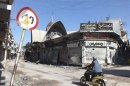 A man rides a motorcycle through the old city of Homs