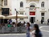 People sit in an outdoor coffee shop in front of an HSBC bank branch in Valletta