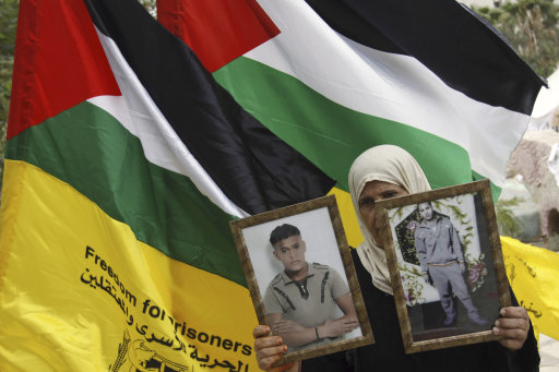 The Palestinian mother of Fatah militants jailed in Israel, Thaer and Mohammed Amarneh holds their pictures during a solidarity protest in the West Bank town of Jenin, Wednesday, Oct. 12, 2011. According to an Israeli Prison Service statement released Sunday, over 200 Palestinian prisoners are currently hunger striking in Israeli prisons, in protest against the worsening of their prison conditions. Palestinian officials said around 2,000 prisoners have joined the strike, demanding better conditions behind bars.(AP Photo/ Mohammed Ballas)