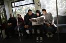 In this photo taken on Wednesday, Sept. 9, 2015, Syrian refugee family, Reem Habashieh, second from right, and her brothers Yaman Habashieh, right, and Mohammed Habashieh, center, sit in a train and read in that day's edition of the local news paper BZ with special pages in Arabic for refugees, on their way from their temporary accommodation facility to the central registration center for refugees and asylum seekers LaGeSo (Landesamt fuer Gesundheit und Soziales - State Office for Health and Social Affairs) in Berlin. Right are the mother Khawla Kreem with the youngest doughtier Raghad Habashieh. The family arrived in Berlin around a week ago, five of the 37,000 who have flooded into Germany this month seeking a new life. (AP Photo/Markus Schreiber)