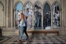People walk in the Cathedral of Bayeux during an exhibition dedicated to the work of French photojournalist Laurent Van Der Stockt in Syria, on October 11, 2014 in Bayeux