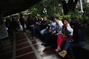 People sit outside a shopping mall during a massive blackout in Caracas