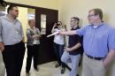 David Ermold, right, attempts to hand Rowan County clerks Nathan Davis, left, and Roberta Earley, second from left, a copy of the ruling from U.S. District Court Judge David Bunning, instructing the county to start issuing marriage licenses, in Morehead, Ky., Thursday, Aug. 13, 2015. Rowan County Clerk Kim Davis has refused the order and has filed an appeal. (AP Photo/Timothy D. Easley)