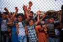 Refugee youths gesture from behind a fence as officals arrive at Nizip refugee camp near Gaziantep
