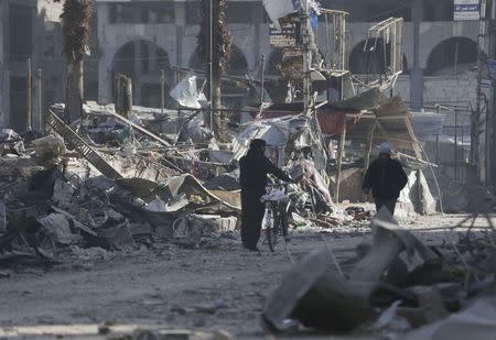 Men walk through a damaged area after what activists said were at least 20 air strikes by forces loyal to Syria's President Bashar al-Assad in the Douma neighbourhood of Damascus