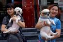 Animal activists hold a dog which was rescued from a dog meat trader and a rescued stray dog, before their gathering against Yulin Dog Meat Festival in Beijing