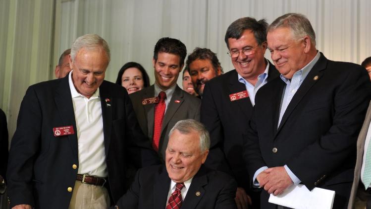 Surrounded by bill supporters, Georgia Gov. Nathan Deal signs House Bill 60 into law during a signing event Wednesday, April 23, 2013, in Ellijay, Ga. The bill makes several changes to the state&#39;s gun law. It allows those with a license to carry to bring a gun into a bar without restriction and into some government buildings that don&#39;t have certain security measures. It also allows religious leaders to decide whether it&#39;s OK for a person with a carry license to bring a gun into their place of worship. (AP Photo/Atlanta Journal-Constitution, Brant Sanderlin) MARIETTA DAILY OUT; GWINNETT DAILY POST OUT; LOCAL TV OUT; WXIA-TV OUT; WGCL-TV OUT