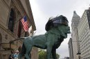 A woman walks past one of the bronze lion statues fitted with an oversized hockey helmet in honor of the Blackhawks run for the NHL Stanley Cup in Chicago
