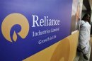 A woman walks past a poster of Reliance Industries installed outside the venue of the company's annual general meeting in Mumbai