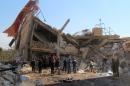 People gather around the rubble of a hospital supported by Doctors Without Borders (MSF) near Maaret al-Numan, in Syria's northern province of Idlib, on February 15, 2016, after the building was hit by suspected Russian air strikes