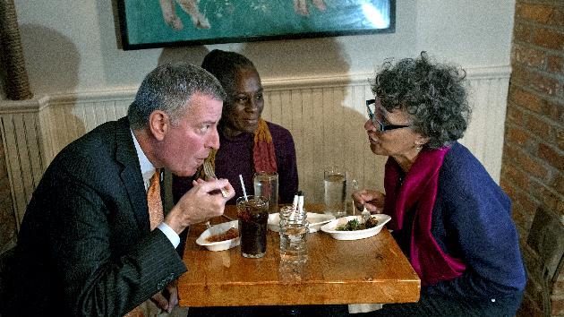 FILE- In this Oct. 25, 2014 file photo, New York City Mayor Bill de Blasio, left, joins his wife Chirlane McCray, center, and New York City Health Commissioner Dr. Mary Bassett for a meal at The Meatball Shop in New York. The restaurant is where Ebola patient, Dr. Craig Spencer, ate just before he became ill with the disease. De Blasio’s actions in the first week of the city’s Ebola crisis were aimed at calming a jittery city, the result of what administration officials say was a studied, carefully planned strategy put in place weeks before. (AP Photo/Craig Ruttle, File)