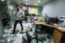 File photo of an employee walking on newspapers after protesters attacked office of Saudi-owned newspaper Asharq al-Awsat in Beirut
