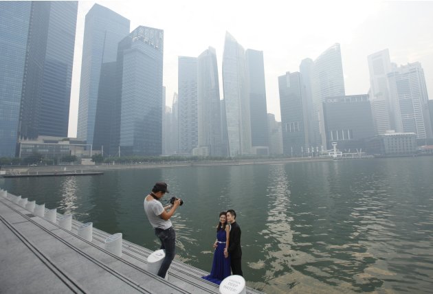 Couple has their wedding photos taken in front of the hazy skyline of Singapore