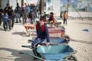 Syrian children wait to carry customers' goods using wheelbarrows, in front of the Tazweed Center at the Al-Zaatari refugee camp in the Jordanian city of Mafraq