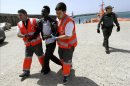 Dos miembros de la Cruz Roja ayudan a uno de los ocho inmigrantes subsaharianos que viajaban en una embarcación hinchable a remos, y que fueron rescatados por un equipo de Salvamento Marítimo, en el puerto de Tarifa. EFE/Archivo