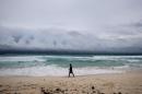 A man walks on the beach as clouds form on the horizon in Cancun