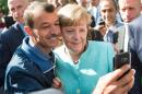 An asylum seeker takes a selfie with Angela Merkel in Berlin on September 10, 2015