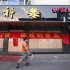 A man walks past a Chinese national flag and a banner covering the entrance to a Japanese restaurant in Suzhou