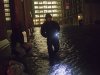 A security guard walks through a flooded street in the financial district of Manhattan