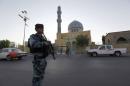 An armed Iraqi policeman stands guard outside a Sunni mosque during Eid al-Fitr prayers in Baghdad