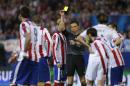 Referee Milorad Mazic shows a yellow card to Atletico's Mario Suarez during the Champions League quarterfinal first leg soccer match between Atletico Madrid and Real Madrid at the Vicente Calderon stadium in Madrid, Spain, Tuesday, April 14, 2015. (AP Photo/Andres Kudacki)