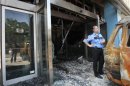 A security guard stands near a damaged van outside the burnt entrance of Microsoft's Greek headquarters at Marousi suburb, north of Athens