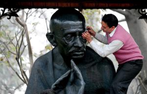 An Indian worker cleans a statue of Mahatama Gandhi …