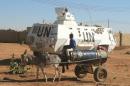 A boy rides a donkey cart as he looks at an armoured personnel carrier belonging to UNAMID stationed in Abu Shok camp, in al-Fasher, the capital of North Darfur state, on December 16, 2013