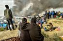 Migrants looks at the smoke rising from fires in the "Jungle" migrant camp in Calais on October 26, 2016