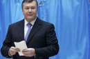 Ukrainian President Viktor Yanukovich holds his ballot as he visits a polling station during the parliamentary elections in Kiev