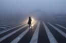 A woman walks along a street during a smoggy day in Changchun