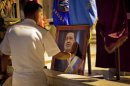 FILE - In this Thursday, Dec. 13, 2012 file photo, a member of Venezuela's navy touches an image of Venezuela's President Hugo Chavez after a mass in support of him in Havana, Cuba. Venezuelan Vice President Nicolas Maduro said late Monday, Dec. 24, 2012 night that he had spoken by telephone with Chavez and that the leader is up and walking following cancer surgery in Cuba. (AP Photo/Ramon Espinosa)