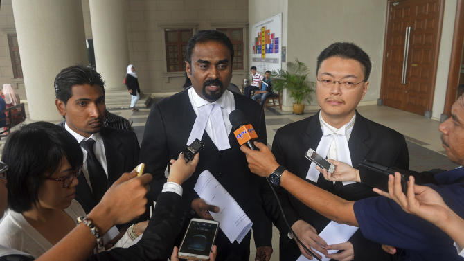 Malaysian lawyer Arunan Selvaraj, center, speaks to journalists outside a courthouse in Kuala Lumpur, Malaysia, Friday, Oct. 31, 2014. Two Malaysian teenage boys on Friday sued Malaysia Airlines and the government over the loss of their father on Flight 370, the first lawsuit filed by the family of a passenger of the jetliner that mysteriously disappeared eight months ago. (AP Photo) MALAYSIA OUT