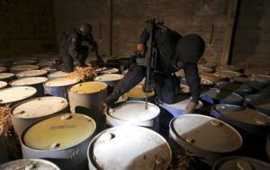 File photo of federal policemen looking at seized barrels they suspect contain the ingredients to make crystal methamphetamines in Apatzingan