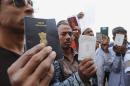 Foreign workers show their passports as they gather outside a Saudi immigration office waiting for an exit permit as Saudi security begin their search campaign against illegal laborers, on November 4, 2013 in downtown of Riyadh