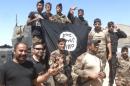 Iraqi security forces stand with an Islamic State flag which they pulled down in the town of Hit in Anbar province