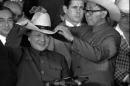 FILE - In this Feb. 2, 1979 file photo, an aide helps Chinese former leader Deng Xiaoping try on a cowboy hat presented to him at a rodeo in Simonton, Texas. One wore a cowboy hat. Another visited Disneyland and Hollywood. Chinese President Xi Jinping's trip to the U.S. this week is the latest in a string of visits made over the years by China's leaders since formal diplomatic relations were established between Washington and Beijing in 1979. (AP Photo, File)