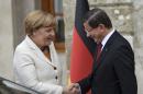 Turkish Prime Minister Ahmet Davutoglu, right, greets Germany's Chancellor Angela Merkel, left, prior to their meeting at his office in Dolmabahce Palace in Istanbul, Sunday, Oct. 18, 2015. Merkel is meeting Turkish leaders to promote a EU plan that would offer aid and concessions to Turkey in exchange for measures to stem the mass movement of migrants across Europe's borders. (Bulent Kilic, Pool Photo via AP)