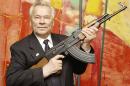 In this July 26, 2002 file photo, Russian weapon designer Mikhail Kalashnikov presents his legendary assault rifle to the media while opening the exhibition "Kalashnikov - legend and curse of a weapon" at a weapons museum in Suhl, Germany. Mikhail Kalashnikov, whose work as a weapons designer for the Soviet Union is immortalized in the name of the world's most popular firearm, has died at the age of 94, Monday Dec. 23, 2013. (AP Photo/Jens Meyer, File)
