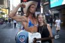 Robert Burck known as the original 'Naked Cowboy' poses for a photo with a woman while wearing his bikini top, which he is wearing due to the recent concerns of topless street performers in Times Square, in the Manhattan borough of New York