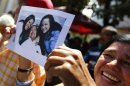 A supporter of Venezuelan President Chavez holds a copy of a photograph of Chavez during a gathering at Plaza Bolivar in Caracas